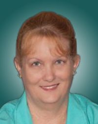 Smiling woman with red hair, wearing a turquoise blouse, set against a soft teal background. This portrait conveys professionalism and approachability.