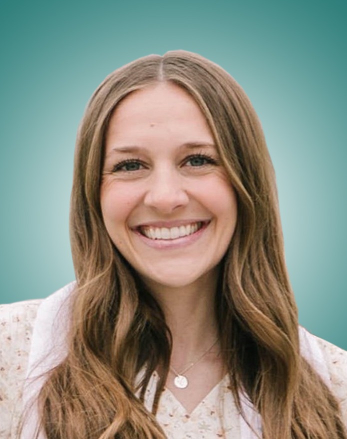 A smiling woman with long, wavy brown hair, wearing a floral top and a necklace, set against a soft teal background.